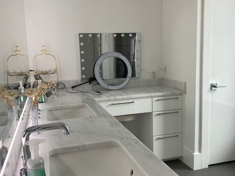 Cleaned marble double-sink bathroom vanity with a lighted makeup mirror after an Enma Cleaning visit in Kenner, Louisiana