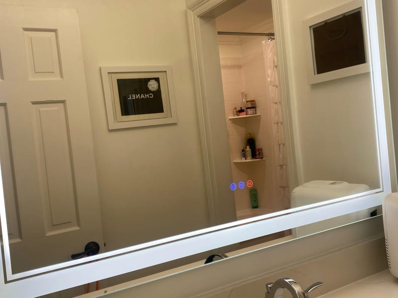 Streak-free framed bathroom mirror above a cleaned white vanity and faucet after an Enma Cleaning service in Kenner, LA